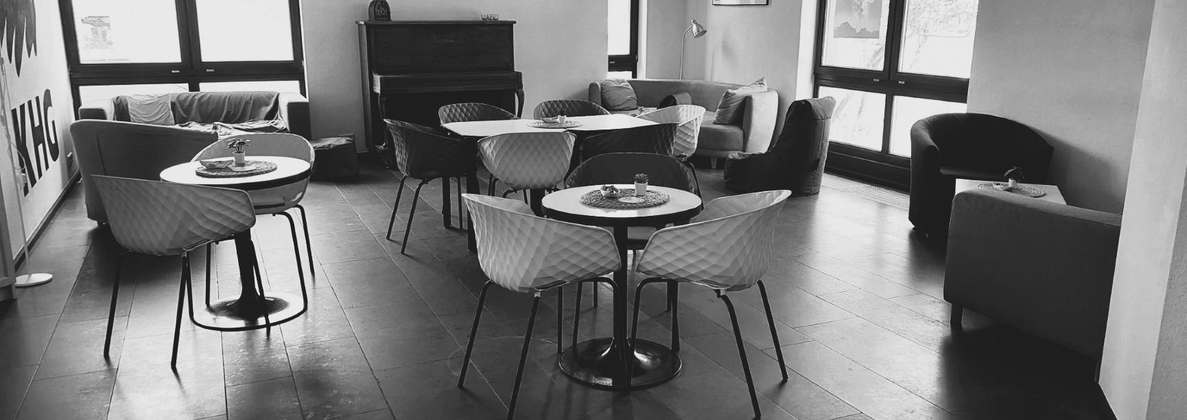 Schwarz-weiß-Foto des Cafés. Man sieht gemütliche Sofas, Tische und Stühle
