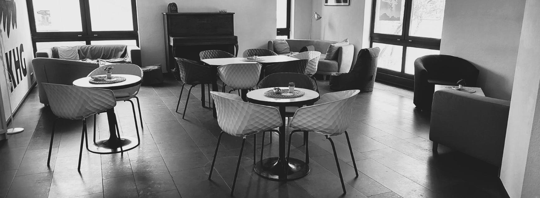 Schwarz-weiß-Foto des Cafés. Man sieht gemütliche Sofas, Tische und Stühle