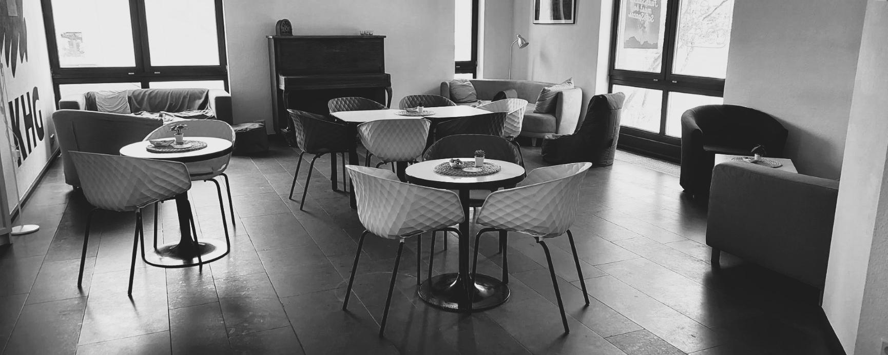Schwarz-weiß-Foto des Cafés. Man sieht gemütliche Sofas, Tische und Stühle