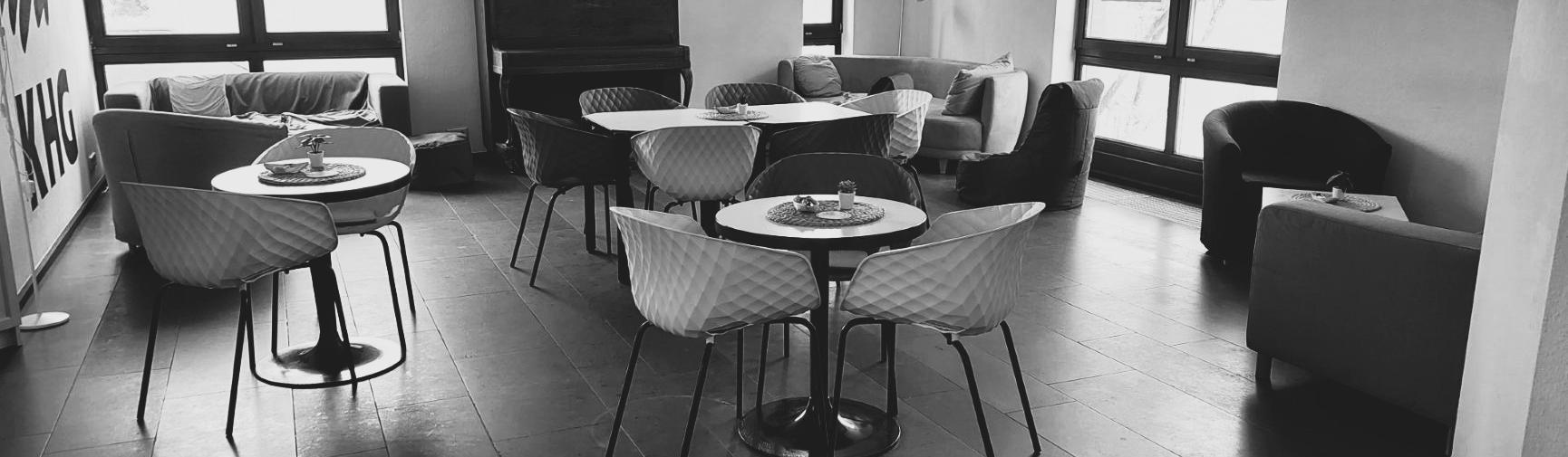 Schwarz-weiß-Foto des Cafés. Man sieht gemütliche Sofas, Tische und Stühle
