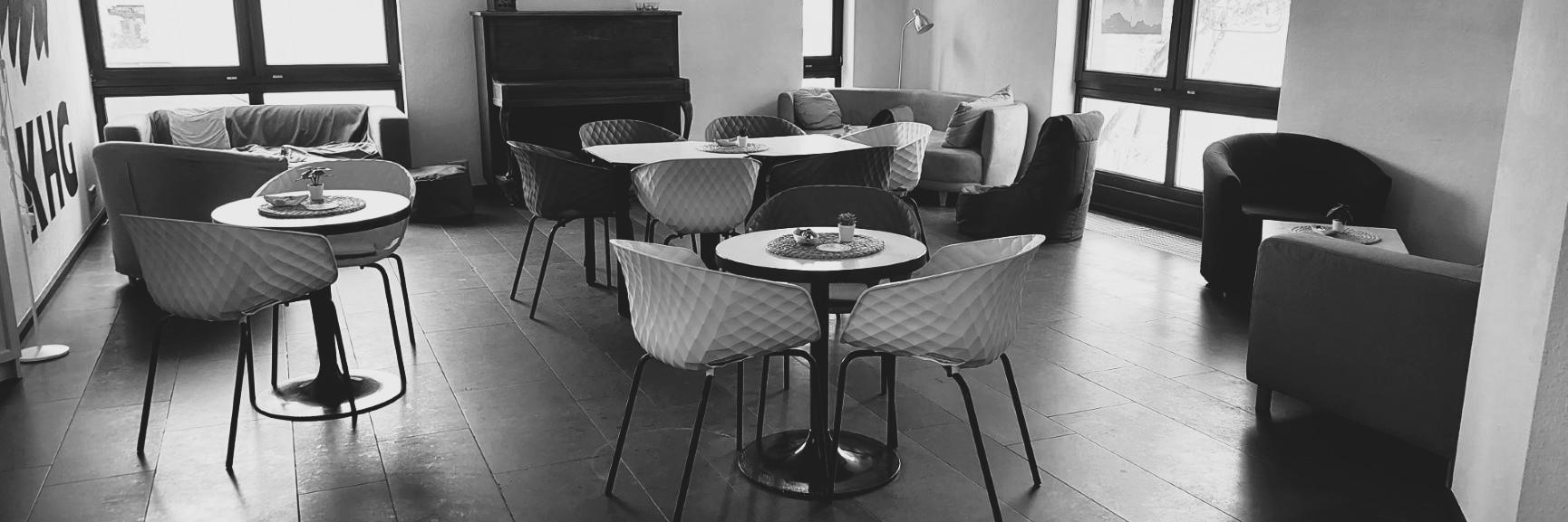 Schwarz-weiß-Foto des Cafés. Man sieht gemütliche Sofas, Tische und Stühle