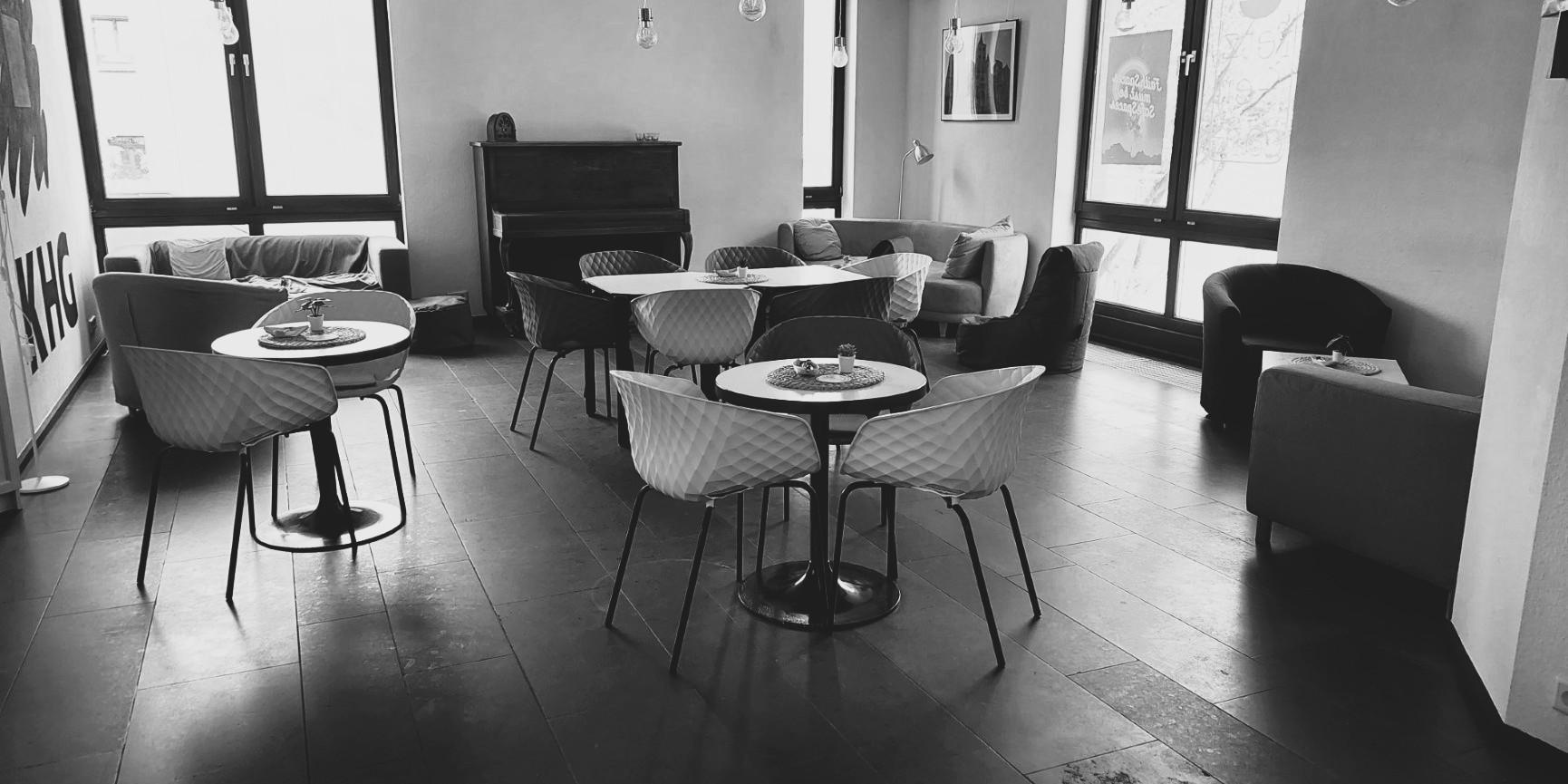 Schwarz-weiß-Foto des Cafés. Man sieht gemütliche Sofas, Tische und Stühle