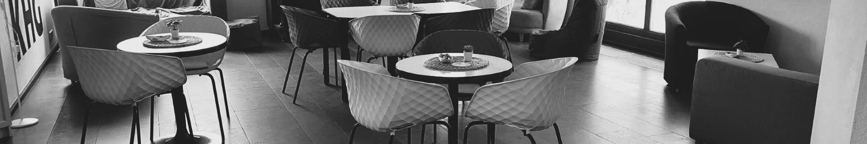 Schwarz-weiß-Foto des Cafés. Man sieht gemütliche Sofas, Tische und Stühle