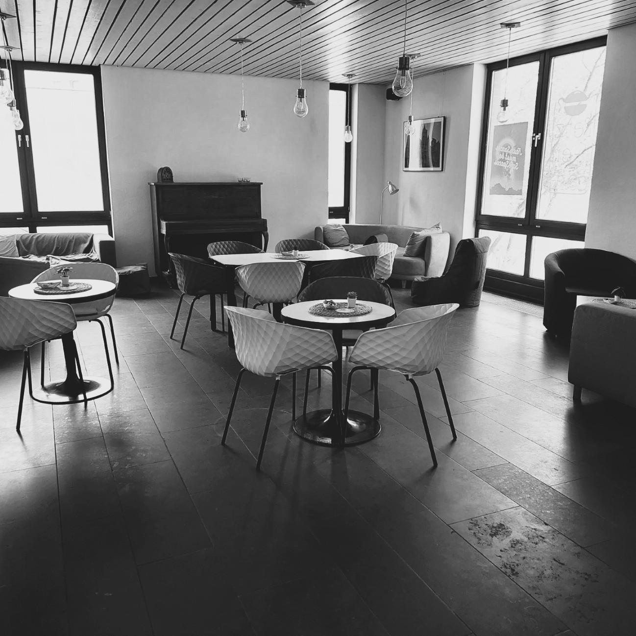 Schwarz-weiß-Foto des Cafés. Man sieht gemütliche Sofas, Tische und Stühle