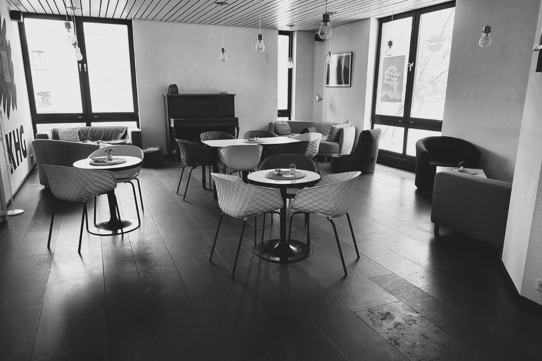 Schwarz-weiß-Foto des Cafés. Man sieht gemütliche Sofas, Tische und Stühle